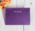 Macro shot of dark purple laser-cut wedding invitation featuring rose patterns and glitter - Deep purple