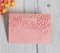 Detail of laser-cut rose patterns on pearlescent pink wedding invitation card - Pink