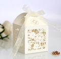 Close-up of laser-cut flower patterns on a cream wedding candy box with white ribbon - Ivory