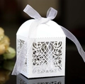 Elegant white laser-cut wedding favor candy box with decorative ribbon on reflective surface - White