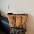 Retro brown suede tote bag with horse charm and dual straps on art books background - Brown