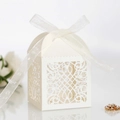 Detail showing white laser-cut hollow candy box with elegant ribbon and vine patterns - Ivory