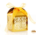 Close-up of golden laser-cut wedding favor box with ribbon bow and elegant hollow pattern - Reflective Gold