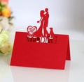 Macro shot of red laser-cut wedding place card with Mr & Mrs silhouette and heart patterns - Pearlescent Red