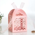 Detail of pink laser-cut favor box with intricate floral patterns and silk ribbon bow - Pink