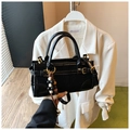 Detalle de bolso en charol negro con acabado brillante y colgante de cuentas decorativo - Con Colgante / Negro