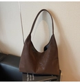 Dettaglio di una grande borsa tote marrone scuro in pelle lucida su un divano in pelle - Marrone