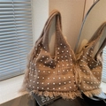 Bolso de punto marrón con perlas blancas y flecos mostrado en el reflejo del espejo - Caqui