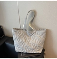 Détail d'un cabas matelassé gris clair avec coutures en S et étiquette de la marque - Gris