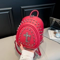Close-up of red leather mini backpack with silver rivets and metal cross detail - Red