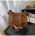 Detalle del bolso tipo cubo marrón caramelo con nudo decorativo y parche de marca de cuero - Marrón