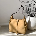 Macro detail of mustard yellow suede shoulder bag with thin leather strap on marble surface - Tan