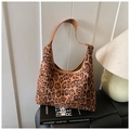 Detail der Vintage-Hobo-Tasche mit Leopardenmuster und braunem Lederriemen auf Buch - Braun