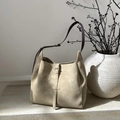 Minimalist beige tote bag with dark brown straps on stone surface with artistic decor - Khaki
