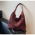 Dettaglio borsa hobo leopardata bordeaux con tracolla in pelle rossa su un divano - Rosso Ankara Leopardato