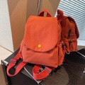 Brick red canvas mini backpack featuring yellow button detail and side drawstring pockets - Orange