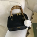 Sac à main noir avec poignée en bambou et pendentif en peluche sur un canapé - Noir avec pendentif
