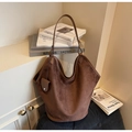 Detalle del bolso tote de ante marrón oscuro con un mini neceser en un mueble retro - café