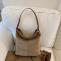 Dettaglio borsa tote in pelle scamosciata marrone con cuciture verticali e tracolla su divano - Cachi