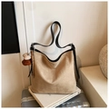 Detail view of khaki suede tote bag with brown plush bear charm on white book - Khaki with Pendant