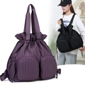 Detail of waterproof pleated nylon fabric and circular embossed logo on women backpack - Purple