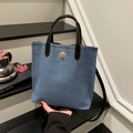 Dunkelblaue Denim-Beuteltasche mit schwarzen Ledergriffen und goldenem Drehverschluss - Hellblau