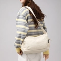 Dettaglio della borsa a tracolla in nylon bianco crema con etichetta laterale e tasche - Bianco Sporco
