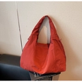 Dettaglio borsa hobo arancione con trama plissettata e coulisse laterale - Borgogna