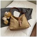 Detail einer braunen Wildleder-Tasche mit gewebter Textur und dekorativem Löwen-Anhänger - Mit Anhänger / Khaki