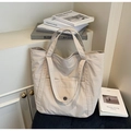 Dettaglio della borsa tote in tela beige con tasca frontale e bottone nero decorativo - Bianco Sporco