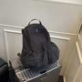 Minimalist black nylon backpack with multi-pocket design on silver suitcase - Black