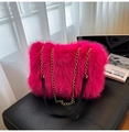 Close-up of bright pink faux fur tote bag with gold metal chain strap on leather seat - Rose Red