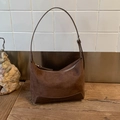 Macro detail of dark brown suede crescent bag with metal zipper and leather stitching - Brown