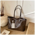 Detail view of large dark brown retro tote bag with fine leather texture on soft stool - Brown