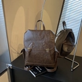 Vintage brown leather backpack with buckle straps and side pockets in a stylish setting - Coffee without Pendant