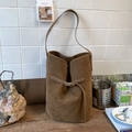 Close-up of coffee brown suede bucket bag texture with retro buckle on wooden table - Brown