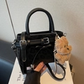 Black leather handbag with bow detail and brown plush bear charm in a lifestyle setting - Black with Pendant