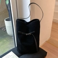 Minimalist black suede bucket bag with long shoulder strap and buckle details - Black