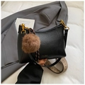 Detail of black leather crescent bag featuring a plush pompom and woven geometric strap - Black with Pendant