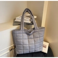 Détail du sac cabas matelassé bleu clair avec motif à carreaux dans un décor élégant - Gris