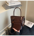 Detail of dark brown bucket bag featuring a wooden bead tassel and smooth leather texture - Coffee