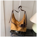 Nahaufnahme der gelben Wildledertasche mit Elefanten-Anhänger auf Designbüchern - Braun