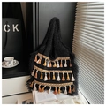Detail of bohemian knitted tote bag featuring vibrant layered tassels in a home setting - Black