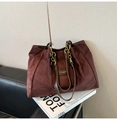 Detailansicht der burgunderroten Wildledertasche mit Goldkette und Markenplakette - Braun