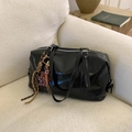Detail of glossy black leather boston bag with leopard heart charm on a sofa - Black with Pendant / Black