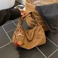 Retro brown hobo tote bag with ethnic tassel charm on dark floor setting - With Charm / Brown