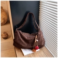 Detailed macro view of dark coffee suede tote texture with ethnic tassel and bead charm - Brown