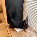 Schwarze Retro-Achseltasche in Matt-Optik mit Schokoladenanhänger auf Holzuntergrund - Schwarz mit Anhänger