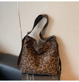 Detailed view of leopard print canvas tote bag with brown leather logo patch on a bench - Dark Brown