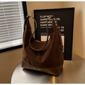 Détail du sac hobo en daim marron foncé avec base en cuir lisse et logo en métal argenté - Marron